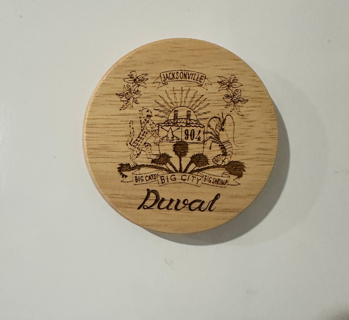 Duval Crest..... Join the Fam!&nbsp;  Show your 904 love with innovative and sleek Wooden Bottle Opener Magnet!&nbsp;  Size 2 3/4 inch diameter &nbsp; &nbsp;1/4 inch depth  Unpolished smooth wood with laser engraved design. Bottle opener and magnet on the back